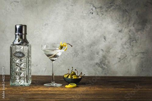 Martini with lemon twist and caperberry, vintage decanter, caperberries in small bowl photo