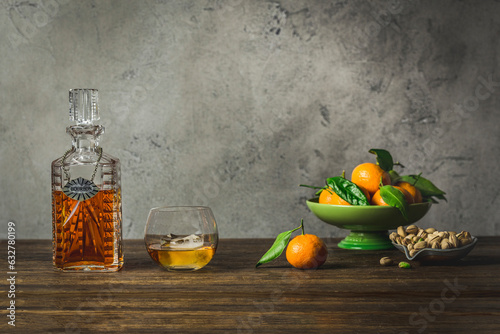 Bourbon in vintage decanter and rocks glass with bowl of mandarin oranges ond bowl of pistachios photo