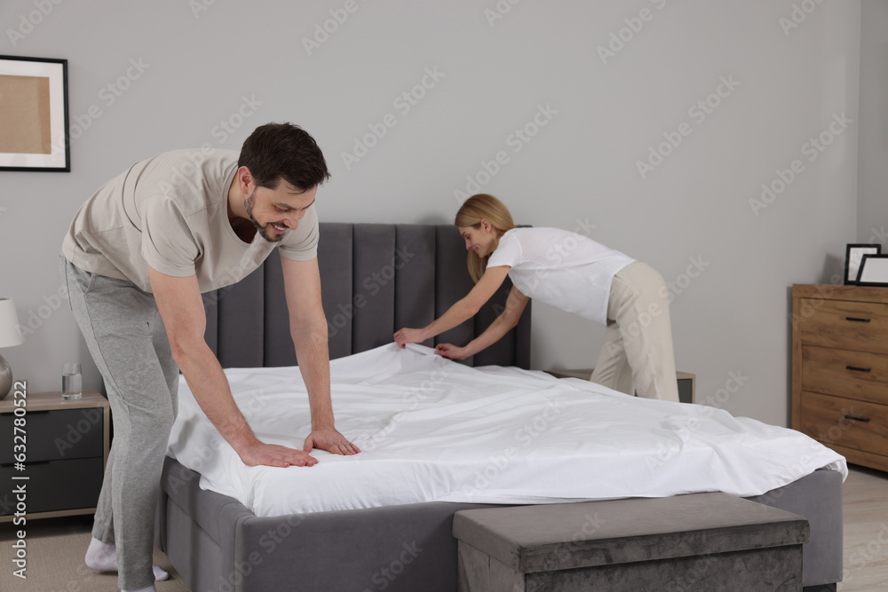Fototapeta premium Couple changing bed linens in room. Domestic chores