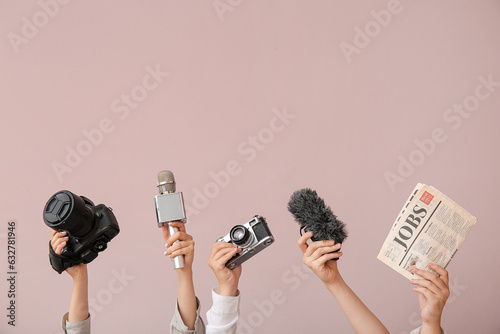 Female hands with newspaper, microphones and photo cameras on color background photo