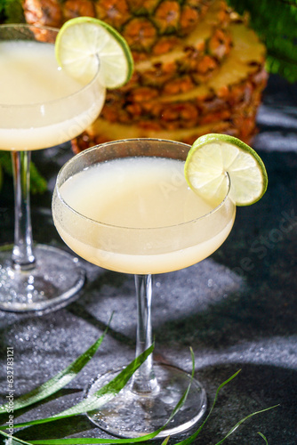 Summer cocktail pineapple daiquiri with vodka, pineapple juice, frozen motion and flying drops. Tropical background with palm leaves photo