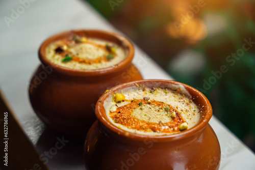 Kulfi or Qulfi ice cream in a clay pot. Kulfi is a popular traditional Indian dessert made of milk with spices and nuts. Two clay pots with ice cream on a blurry background