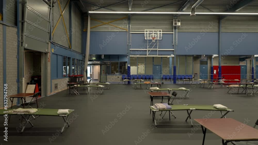 Refugee shelter on basket ball sports hall bed and table line up dolly shot