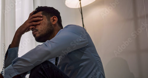 A businessman sitting on the floor depressed and stressed with problems in his life.