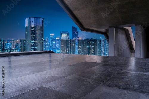 empty concrete floor with modern cityscape in downtown at night.