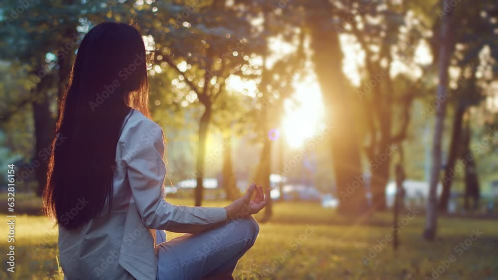 Young woman is sitting on grass in lotus position and meditating in ...