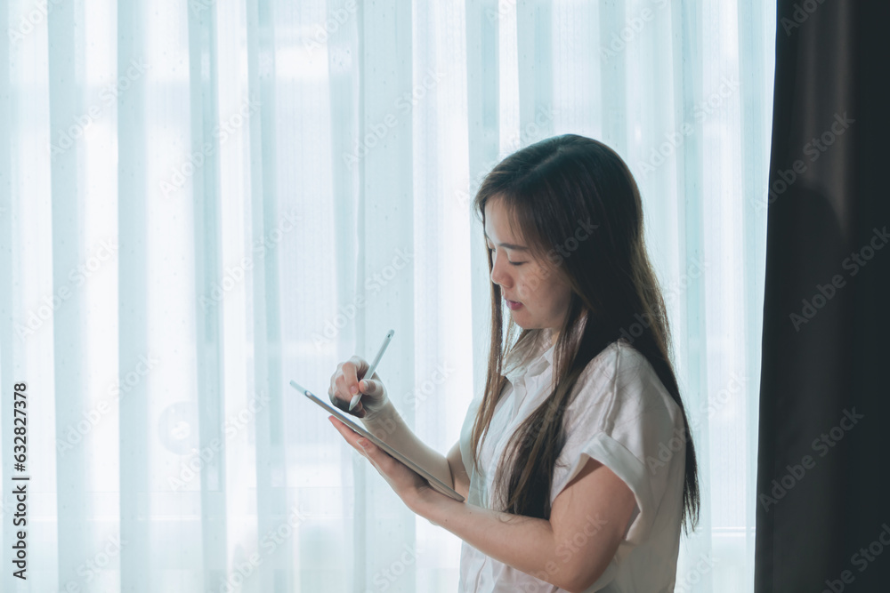 Asian woman using tablet pc in living room at home, business concept. Asian woman using tablet pc in living room at home, business concept.