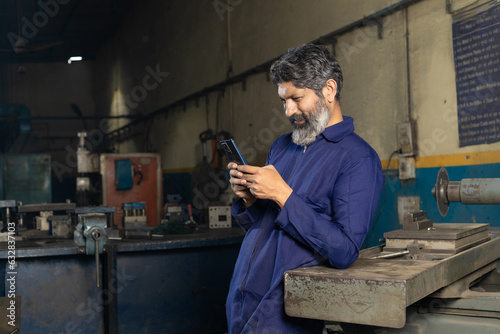Indian worker using smartphone at factory.