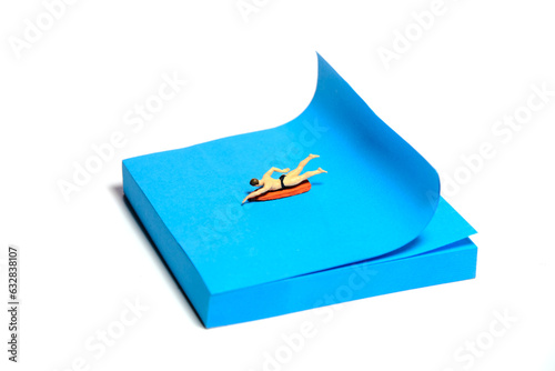 Creative miniature people toy figure photography. Sticky notes installation. A men surfer swimming above surfing board. Isolated on white background.