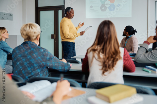 Black senior man giving presentation during education training class in lecture hall.