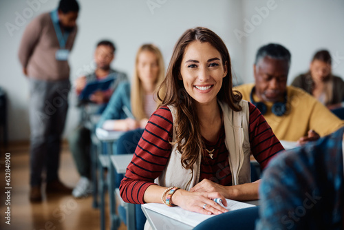 Happy female student learning in classroom and looking at camera. photo