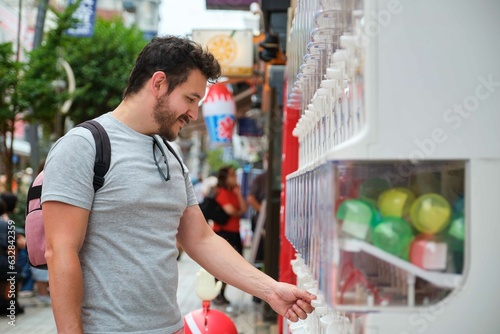 Latin tourist buying a toy capsule at gashapon vending machine in Tokyo, Japan. photo