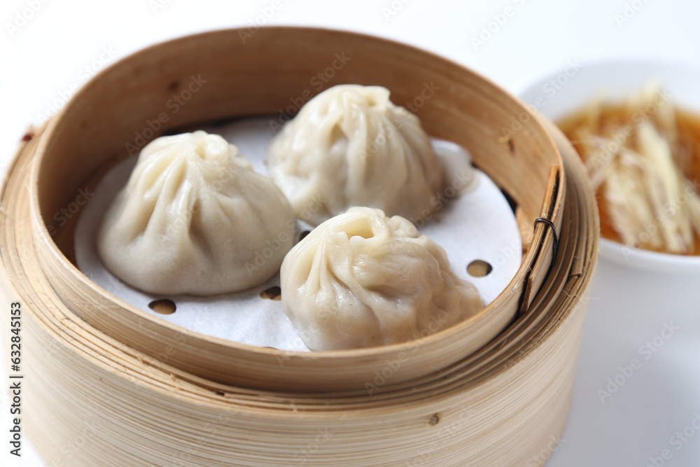 steamed Xiao long bao Shanghai small meat dumpling soup in bamboo basket with ginger vinegar on white background dim sum halal food breakfast menu for Hong Kong cafe steamed Xiao long bao Shanghai small meat dumpling soup in bamboo basket with ginger vinegar on white background dim sum halal food breakfast menu for Hong Kong cafe