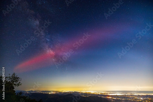 Milky Way galaxy core and red glow from SpaceX rocket launch. Lights of San Diego County below.