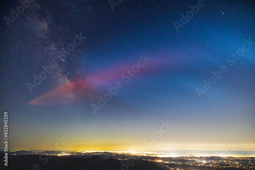 Milky Way galaxy core and red glow from SpaceX rocket launch. Lights of San Diego County below. photo