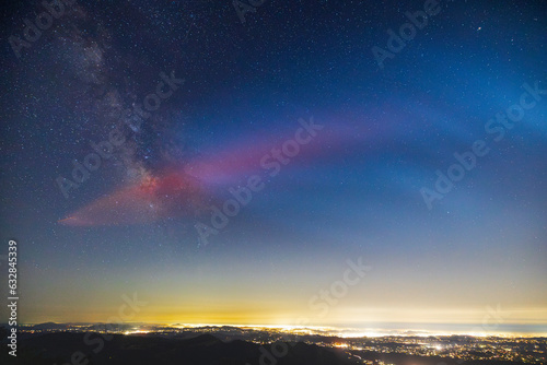 Milky Way galaxy core and red glow from SpaceX rocket launch. Lights of San Diego County below.