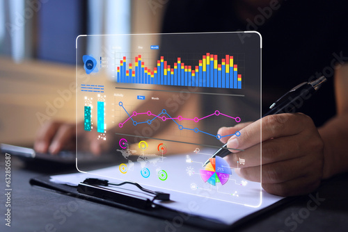 Businessman reading data in bar graph and pie chart form on virtual data analytic dashboard in office. Business analysis for investment and online digital marketing photo