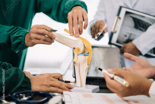 serious doctors team are analyzing fracture knee model showing the process of osteoarthritis patients and knee arthroplasty.