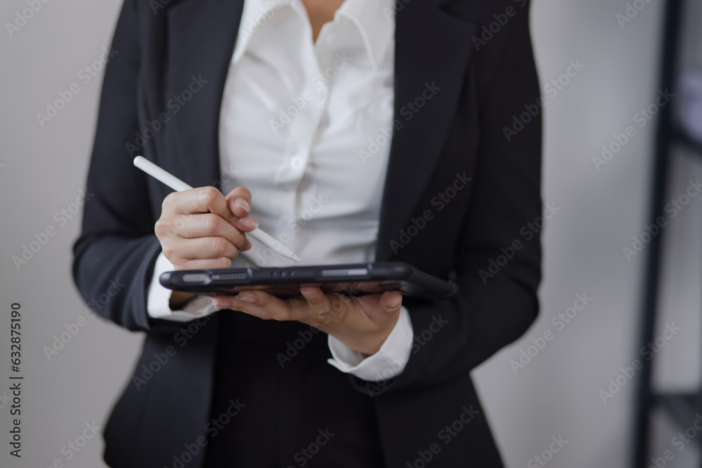 Businesswoman stands with a tablet in hands standing in office. Businesswoman stands with a tablet in hands standing in office.