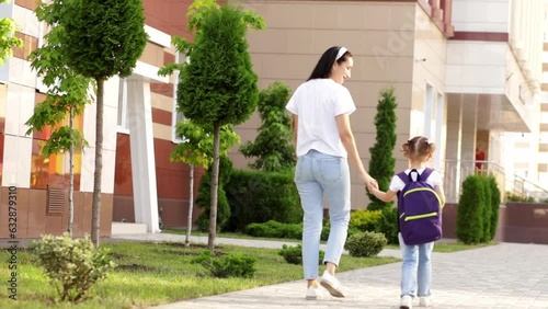 the first day of school, a parent leads a girl to a schoolgirl with a backpack by the hand to the first class, and back to school