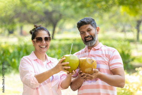 Happy Indian couple drinking coconut water at park.