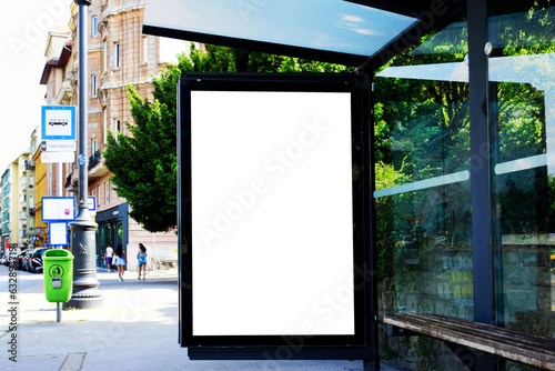 bus shelter. blank ad panel. billboard display. blank white lightbox poster sign at bus stop. digital glass panel. city transit station. urban street. green street setting. outdoor poster advertising
