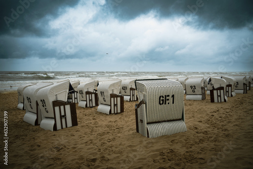 Fototapeta Naklejka Na Ścianę i Meble -  Roofed wicker beach chairs at the baltic sea beach, coast at the island of Usedom in Germany, storm and rain over the brackish water, high waves, storm warning
