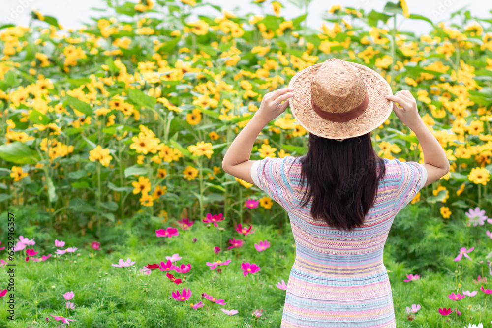 young woman blessed the view of flower garden that looks beautiful in summer alone. Young woman tourists admiring beauty of summer scenery and beautiful flower gardens Copy Space for text