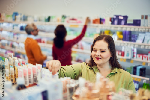 A pretty looking for a cream for skin care while man and women shopping behind.