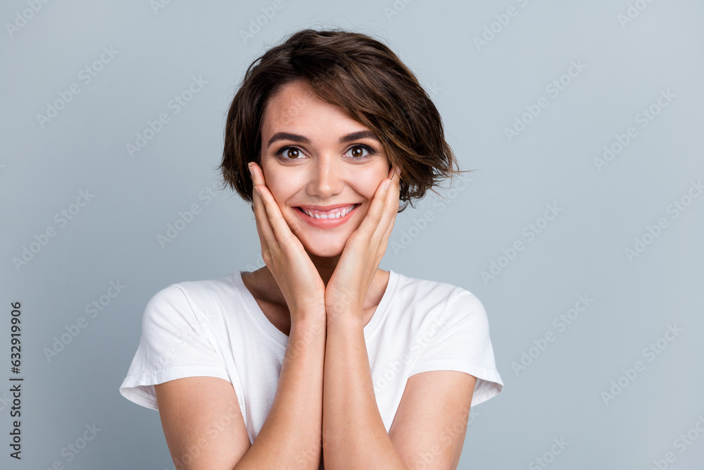 Portrait of adorable positive girl arms touch cheeks beaming smile empty space ad isolated on grey color background Portrait of adorable positive girl arms touch cheeks beaming smile empty space ad isolated on grey color background