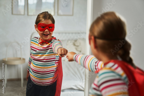 Caucasian girl wearing superhero costume next to the mirror