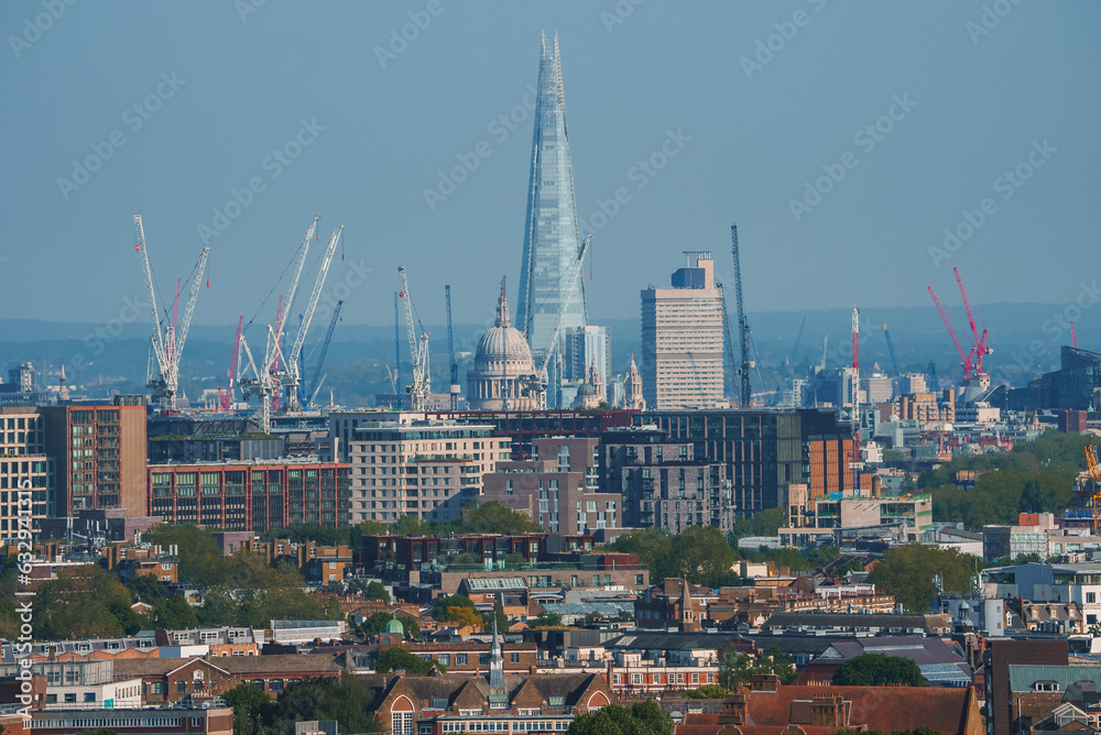 Scenic view of cityscape with blue sky in background. Skyscraper and cathedral amidst residential buildings in London. High angle view of modern development.
