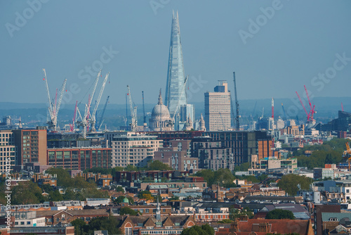 Scenic view of cityscape with blue sky in background. Skyscraper and cathedral amidst residential buildings in London. High angle view of modern development.