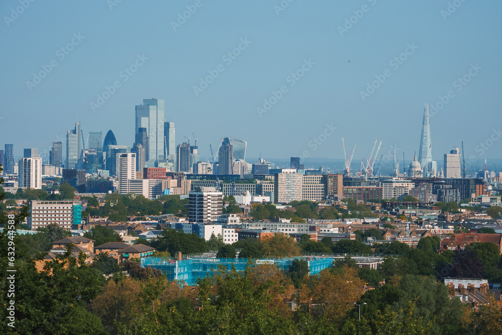Scenic view of London cityscape with blue sky in background. Modern skyscrapers amidst residential buildings. High angle view of urban development in London.