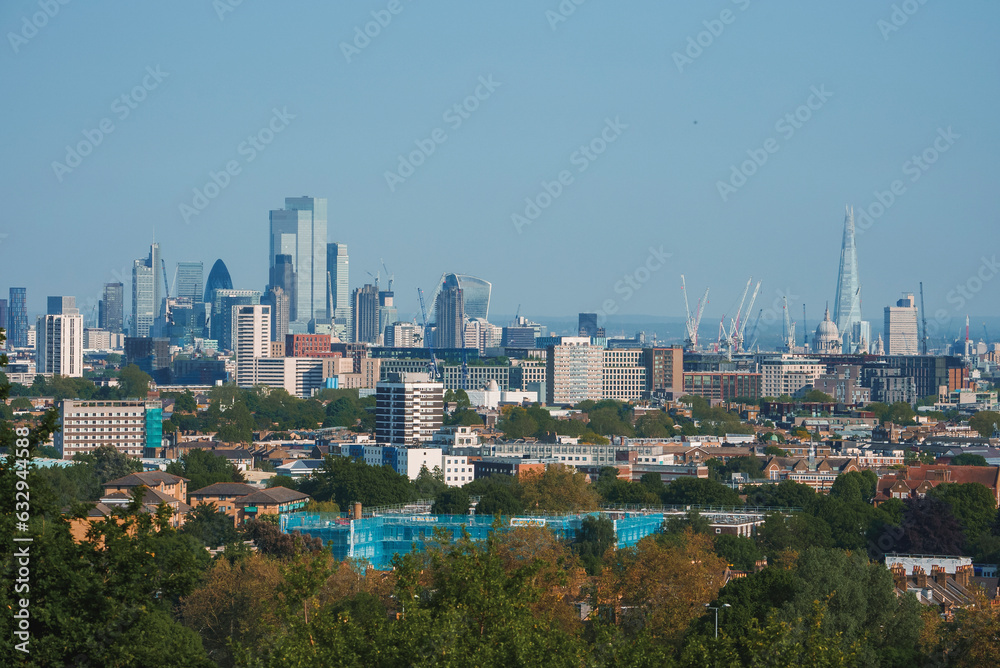 Fototapeta premium Scenic view of London cityscape with blue sky in background. Modern skyscrapers amidst residential buildings. High angle view of urban development in London.