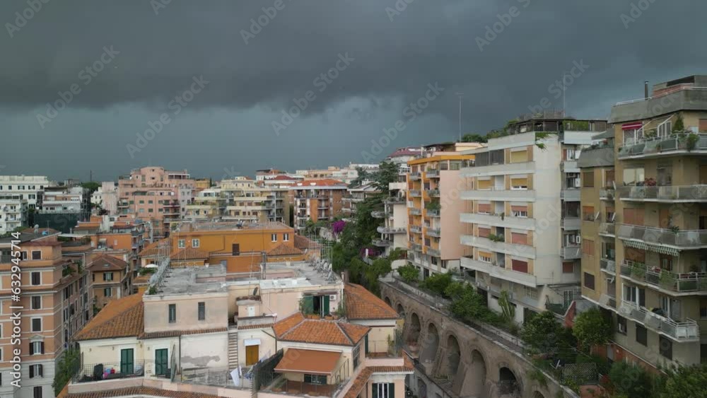 Aerial drone forward moving shot of residential buildings along hilly terrain with dark rain clouds passing over the city of Rome in Italy. Aerial drone forward moving shot of residential buildings along hilly terrain with dark rain clouds passing over the city of Rome in Italy.