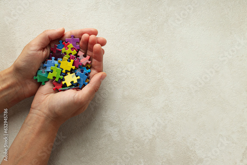 Multicolored puzzle pieces in hands on a light background, place for text. World autism day concept