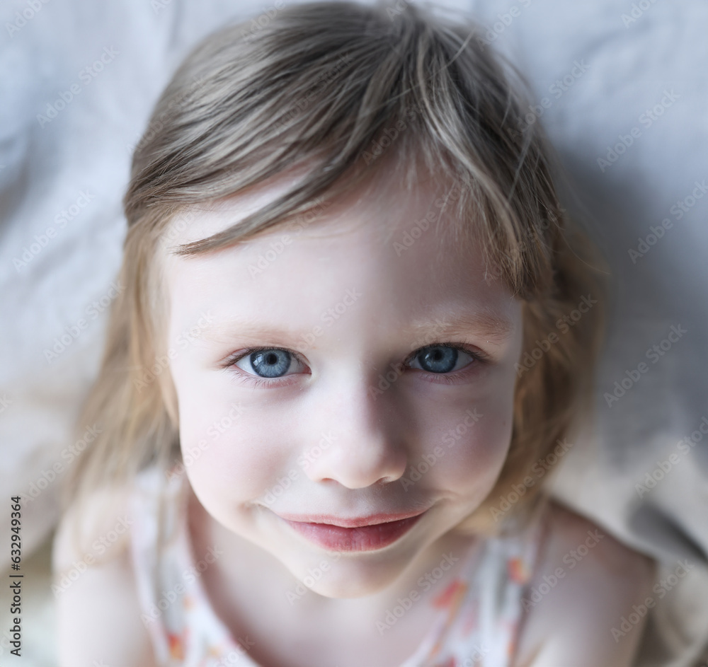 Portrait of smiling little girl with blue eyes in bed. Baby sleep and day routine concept Portrait of smiling little girl with blue eyes in bed. Baby sleep and day routine concept