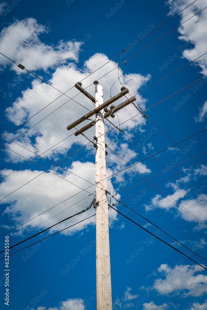 Electricity pole and power lines against the blue sky with white clouds. Summer forest landscape in Nova Scotia, Canada. Electricity pole and power lines against the blue sky with white clouds. Summer forest landscape in Nova Scotia, Canada.