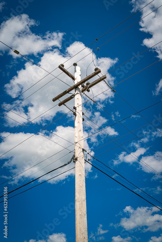 Electricity pole and power lines against the blue sky with white clouds. Summer forest landscape in Nova Scotia, Canada.