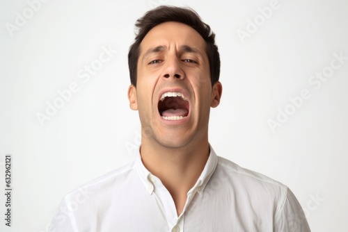 Medium shot portrait photography of a man in his 30s grimacing and touching his throat due to strep throat wearing a simple tunic against a white background 
