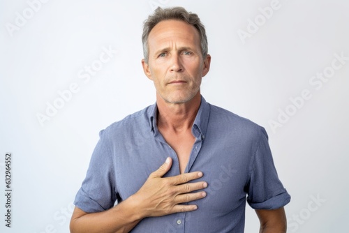 Medium shot portrait photography of a man in his 40s clutching his chest due to gastroesophageal reflux disease wearing a simple tunic against a white background  photo