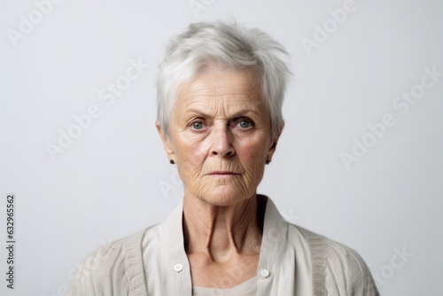 Medium shot portrait photography of a woman in her 60s with furrowed brows and a tense expression due to hypertension wearing a chic cardigan against a white background 