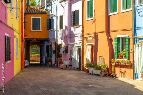 Fototapeta Naklejka Na Ścianę i Meble -  Colourful houses and buildings on a quiet courtyard.  Bright green shutters for the windows and clothes lines or wash lines with laundry. Burano, Venice, Italy