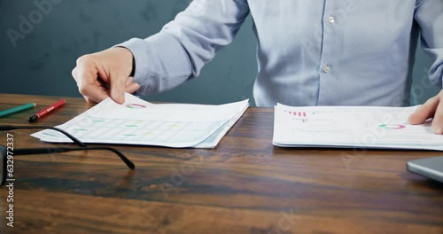 Trader observes paper reports of crypto trading charts growth at wooden table. Cryptocurrency market broker checks analysis of present cryptocurrency