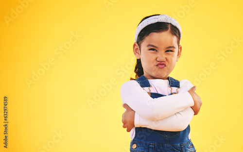 Canvas Print Arms crossed, portrait and angry girl child in studio with bad, attitude or behavior problem on yellow background