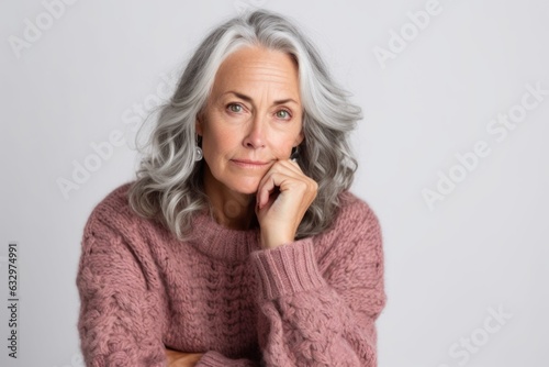 Medium shot portrait photography of a woman in her 50s showing tiredness and a worn-down expression due to chronic fatigue syndrome wearing a cozy sweater against a white background 