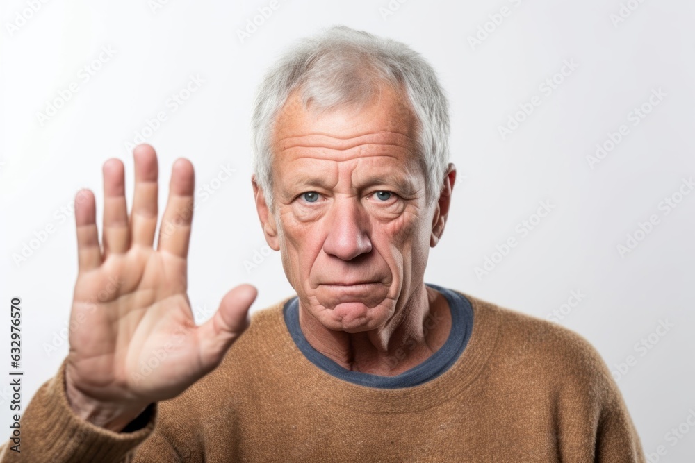Lifestyle portrait photography of a man in his 60s with a trembling hand and pained expression due to Parkinson disease wearing a cozy sweater against a white background Lifestyle portrait photography of a man in his 60s with a trembling hand and pained expression due to Parkinson disease wearing a cozy sweater against a white background