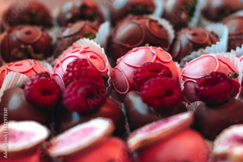 Pink chocolate covered strawberries with fresh raspberries on top. Candies and sweets collection. Tasty set for holidays. Macro