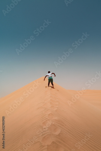 Boy running up sand dune